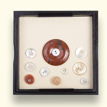 Jaspis Rouwknoop, in het kistje omringd door knoopjes van dierbaren. Deze zijn met kristallen spelden vastgezet. Maten: L x B = ong. 125x125mm