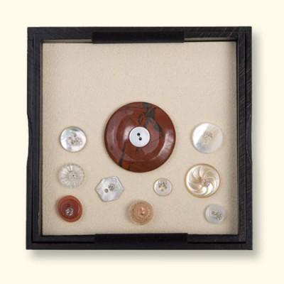 Jaspis Rouwknoop, in het kistje omringd door knoopjes van dierbaren. Deze zijn met kristallen spelden vastgezet. Maten: L x B = ongeveer 125x125mm