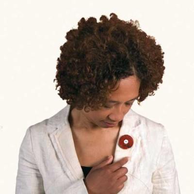 Vrouw draagt een jaspis rouwknoop als broche op een wit jasje.