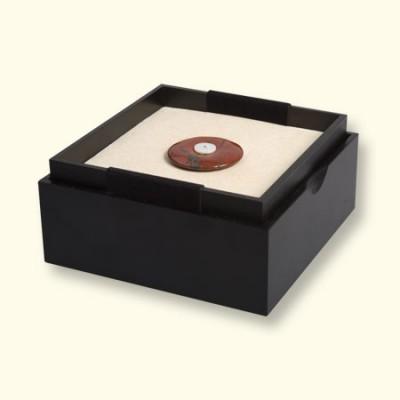 Jaspis Rouwknoop ligt in het open kistje op de gele zijde van het omkeerbare kussentje. De andere kant is grijs. Maten: L x B = ongeveer 125x125mm