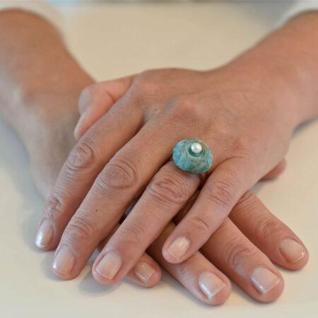 Onder de cabochon (het kapje op de ring) van brons, zilver of gepatineerd brons is ruimte om wat as, aarde of een haarlokje te bewaren.