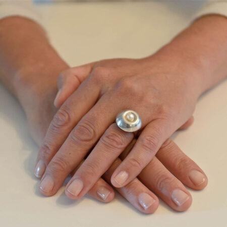 Onder de cabochon (het kapje op de ring) van brons, zilver of gepatineerd brons is ruimte om wat as, aarde of een haarlokje te bewaren.