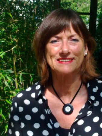 Vrouw draagt een hanger met een zwarte onyx Rouwknoop met een knoopje van haar dierbare. De zwarte onyx is altijd egaal van kleur.