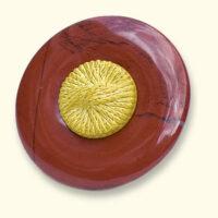 Een jaspis Rouwknoop met een geel knoopje van een dierbare erop. De rode jaspis is vaak geaderd.