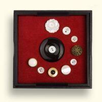 Onyx Rouwknoop, in het kistje omringd door knoopjes van dierbaren die met kristallen spelden zijn vastgezet. Maten: L x B = ong. 125x125mm