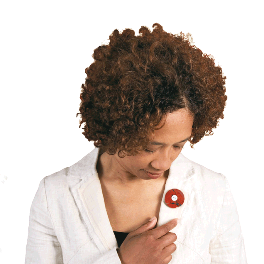 Vrouw bekijkt liefdevol haar jaspis Rouwknoop. | parlAmore© De Rouwknoop kun je dragen als hanger, reversspeld en broche. Hier draagt een jonge vrouw een jaspis Rouwknoop als broche op haar jasje.