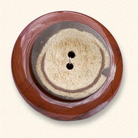 Een jaspis Rouwknoop met een houten jasknoop van een dierbare erop. De rode jaspis is vaak geaderd.