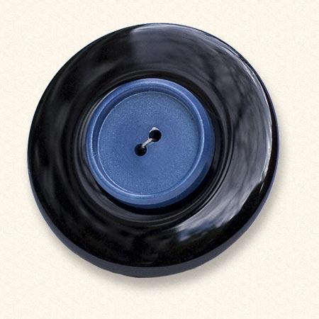 Een onyx Rouwknoop met een blauwe jasknoop van een dierbare erop. De zwarte onyx is altijd egaal van kleur.